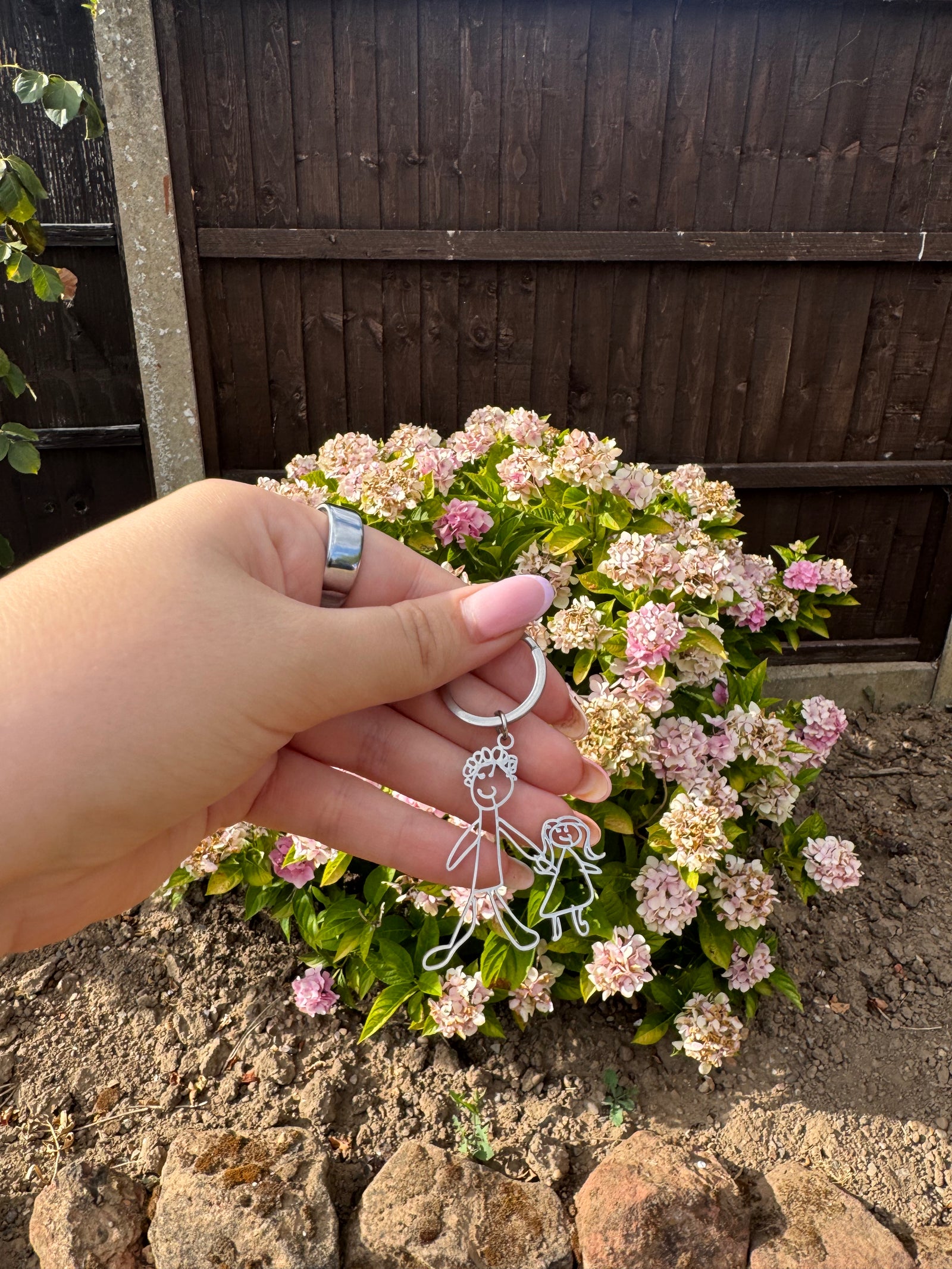Personalised keyring held outdoors among flowers